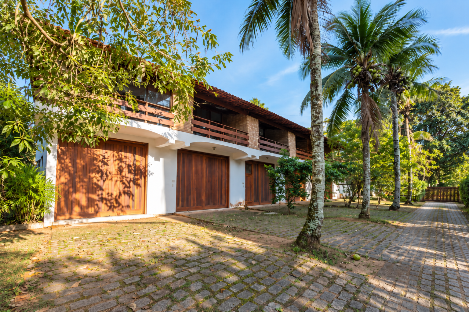 Casa cercada por jardim tropical com a marina ao fundo no Saco da Ribeira